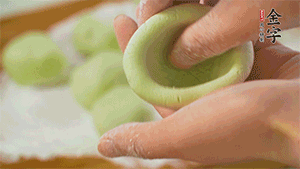 將均分的艾草面團搓成圓，挖一個窩，放入餡心，再搓成圓。