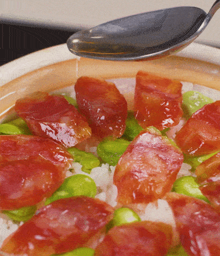 大米出現(xiàn)小孔時開蓋放香腸，往鍋邊淋入少許油，再燜煮8~10分鐘左右。