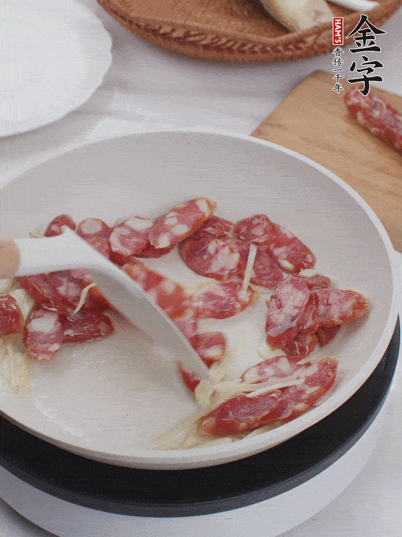 油溫3成熱時(shí)，下姜絲、蒜片、香腸炒出油脂。