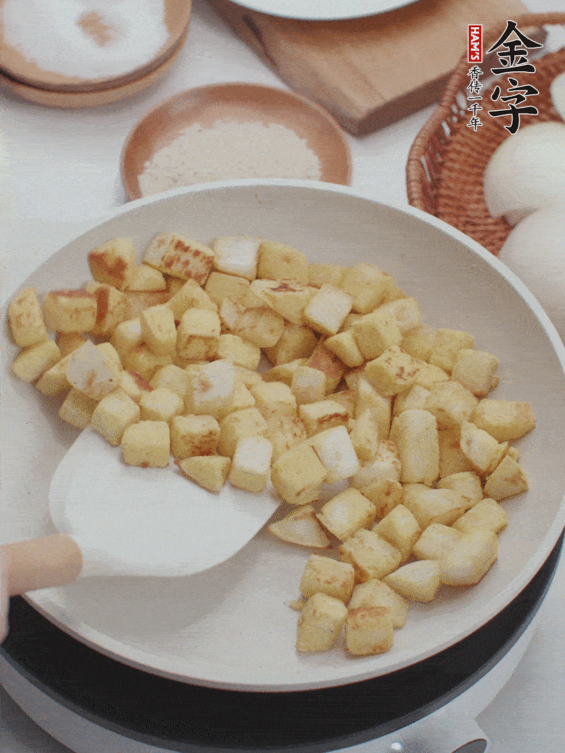 起鍋熱油，倒入饅頭丁，小火煎至蛋液凝固定型再翻面，饅頭丁部煎至金黃時(shí)盛起待用。