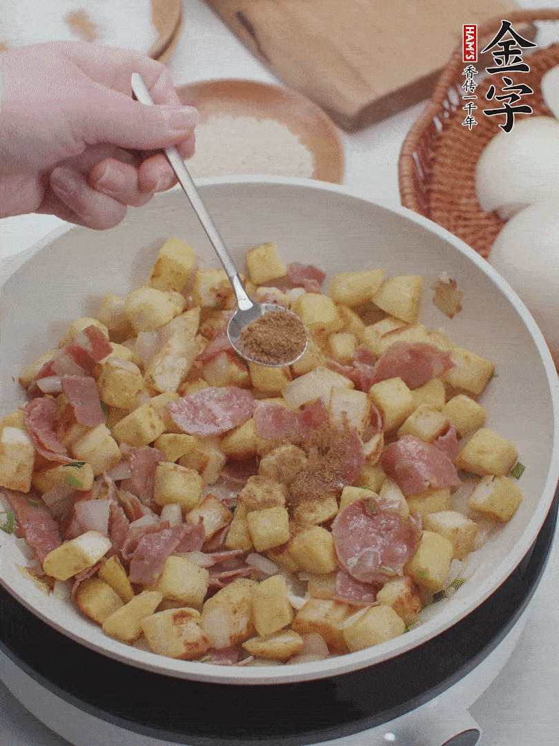 起鍋少油，煸香洋蔥丁、蔥白，加入金字培根火腿翻炒幾下，再加入饅頭丁、1小勺孜然粉、少許鹽翻炒均勻并鋪平。