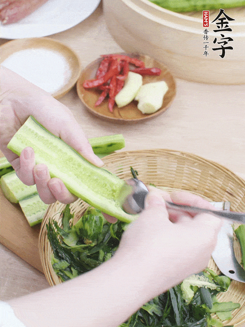黃瓜削皮，對半切開，勺子挖去內(nèi)瓤，斜刀切片。青蒜斜刀切段。