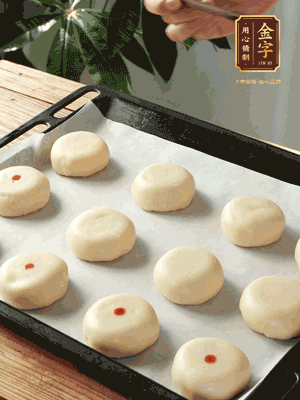 收口向下放在案板上，輕輕將月餅坯按扁，用筷子點紅點做裝飾