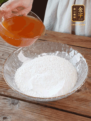 轉(zhuǎn)化糖漿、枧水、花生油攪拌均勻，加入面粉混合，醒發(fā)2小時(shí)。捏成23g一個(gè)的小球