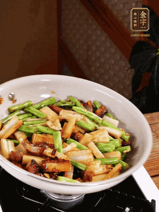 油熱下蒜末、干辣椒、醬肉煸炒出香味，依次下藕條、豆角翻炒均勻